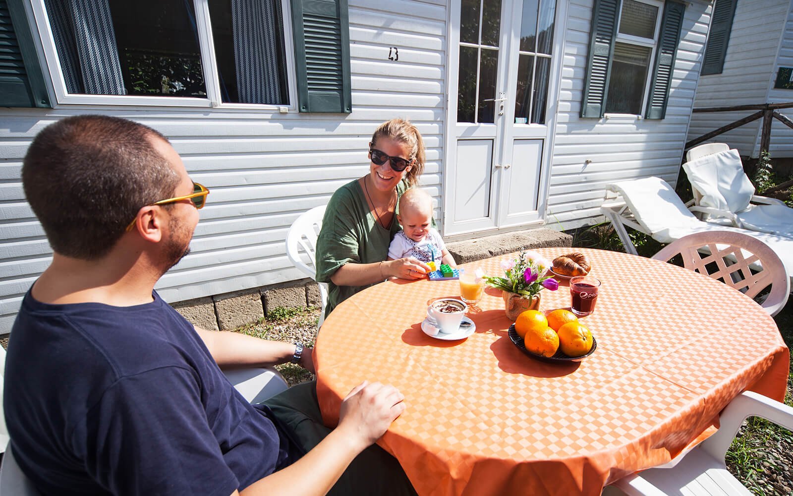 Family sitting at table outside holiday home